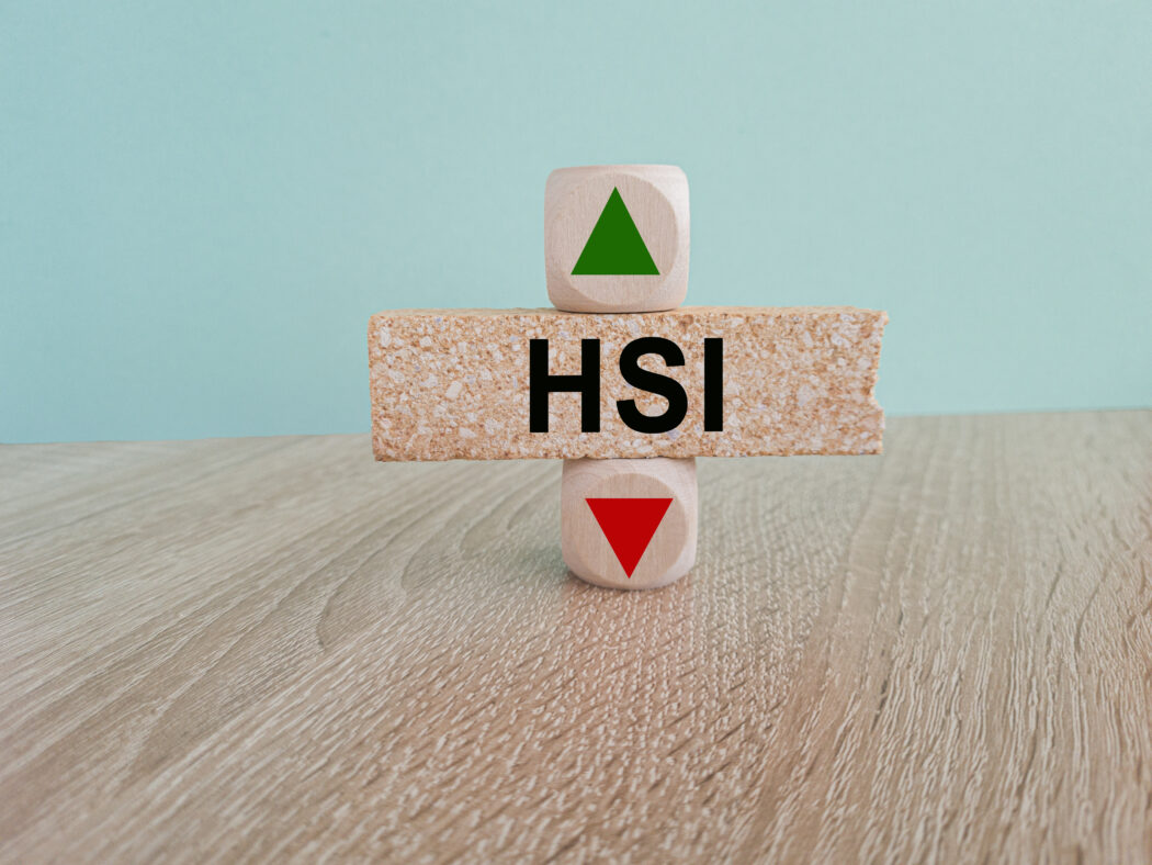 HSI price symbol. A brick block with arrow symbolizing that Hang seng index price are going down or up. Beautiful blue background. Business and gold price concept. Copy space.
